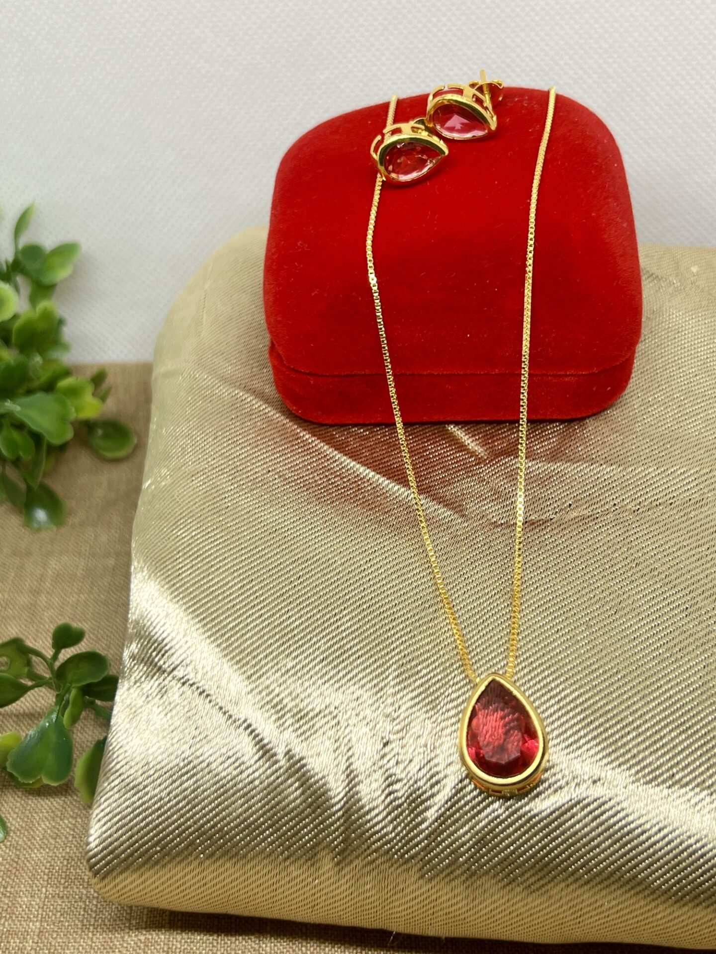 O conjunto colar e brinco coração vermelho banhado a ouro 18k é a personificação da elegância e do amor. Com detalhes minuciosamente trabalhados, este conjunto é ideal para quem deseja adicionar um toque sofisticado e romântico ao seu visual.